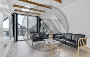 Ein modernes Schlafzimmer im Loft-Stil mit einem großen Oberlicht, einer Couch, einem Couchtisch und Blick ins Freie.