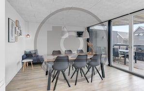 Ein moderner Essbereich mit Glastrennwand, einer Couch und einem Esstisch mit Stühlen.
