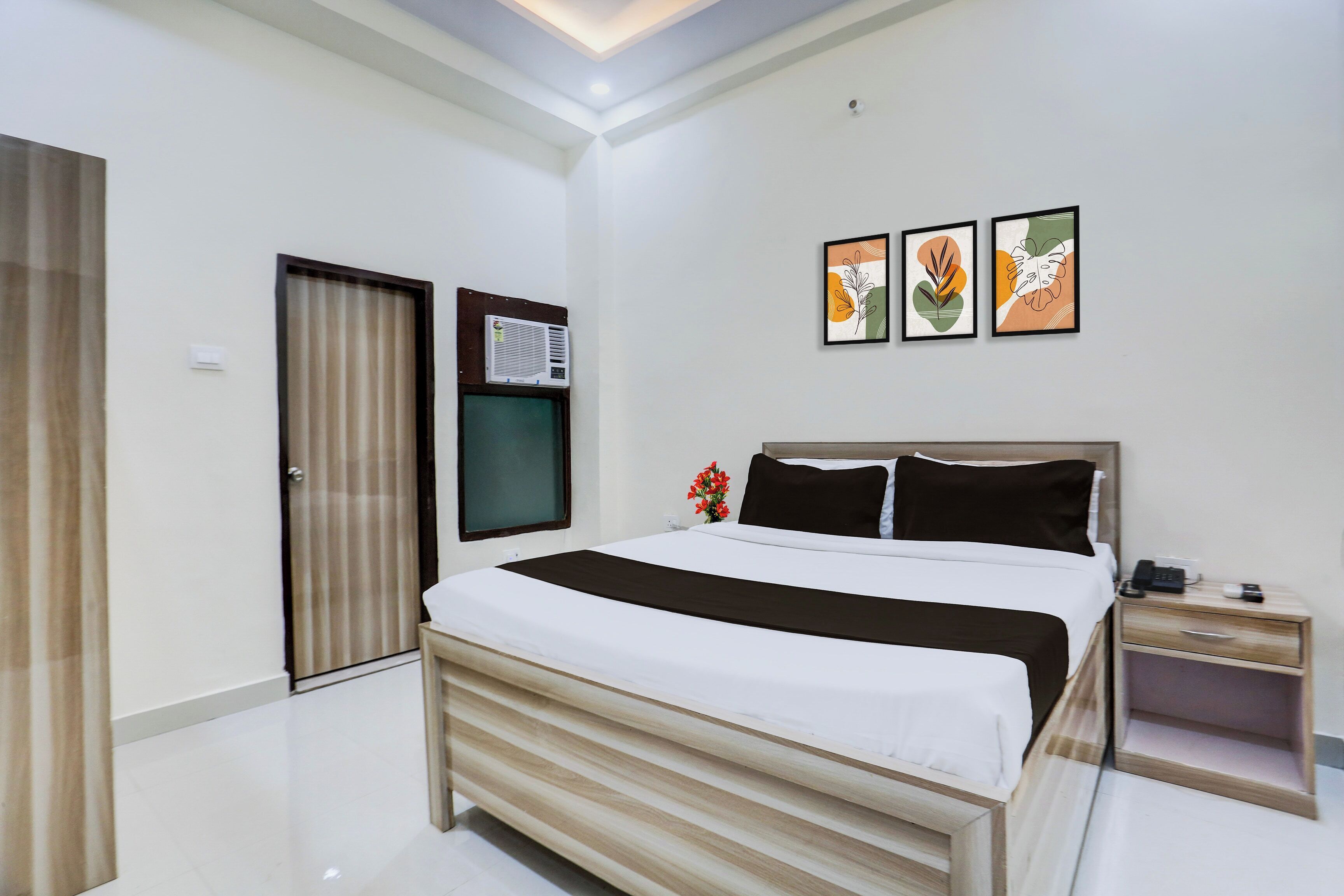 Una habitación de hotel con cama, mesita de noche y aire acondicionado de pared.