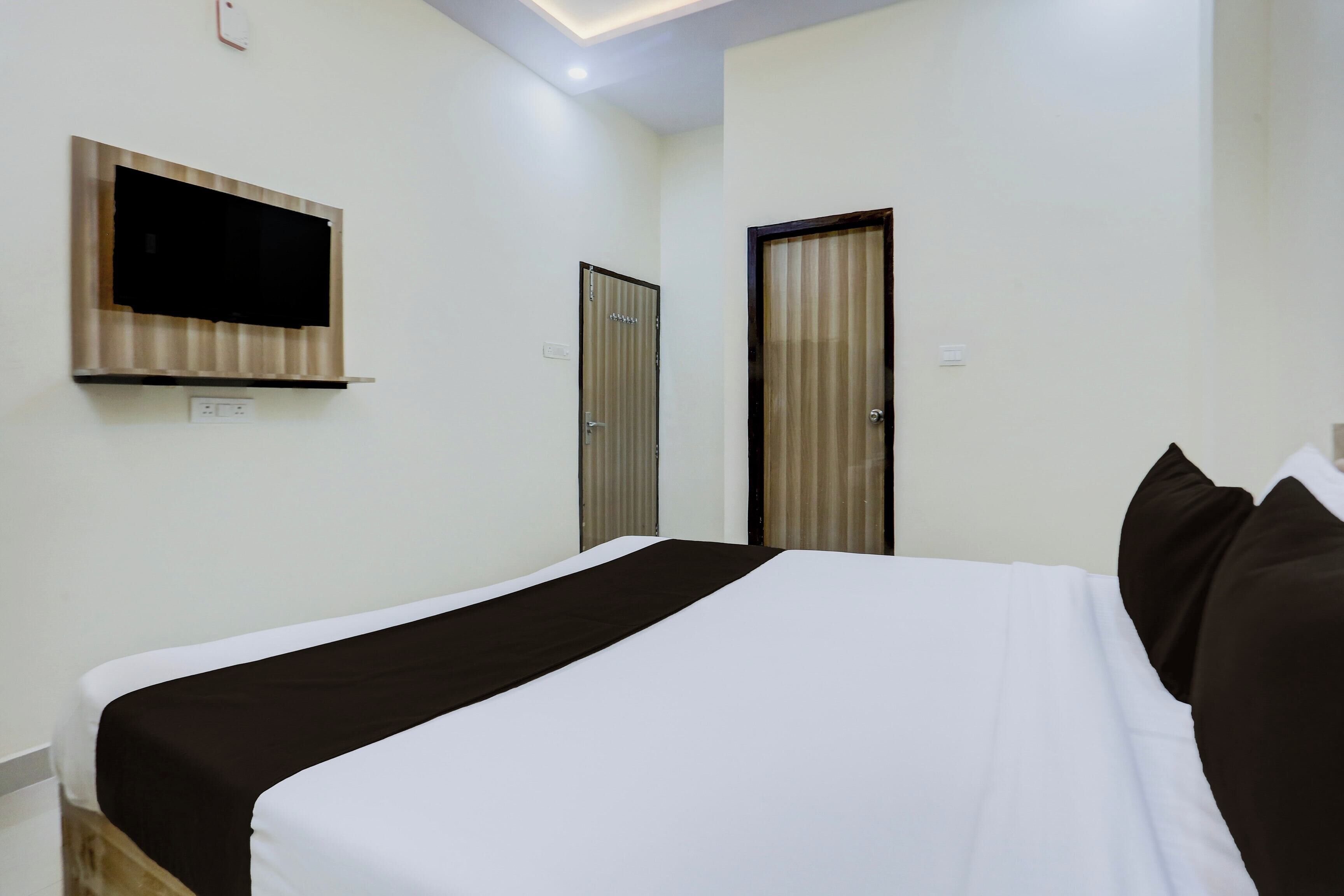 Een hotelkamer met een bed, een aan de muur bevestigde televisie en twee deuren.