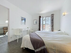 A bedroom with a bed, a desk, a chair, and a window with curtains. - Claire Joie by Interhome (Saint Brevin les Pins)