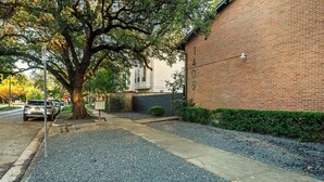 A brick building with a gravel driveway and a tree in front. - The Montrose Hideaway, Downtown, Medical Center 07 (Houston)