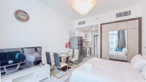 A hotel room with a bed, a TV, a dining area, a kitchen, and a bathroom. - Pearlz By Danube Residences - Al Furjan (Dubai)