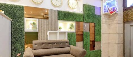 A lobby with a sofa, a coffee table, and a clock displaying times for New Delhi, Tokyo, and New York.