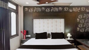 A hotel room with a large bed, a bedside table with a lamp, and a decorative wall. - Collection O Kanpur Central Railway (Kanpur)