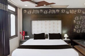 Una habitación de hotel con una cama grande, una mesita de noche con lámpara y un adorno en la pared.
