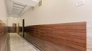 A corridor with a tiled floor, a brick wall on one side, and a door at the end. - Collection O Kanpur Central Railway (Kanpur)