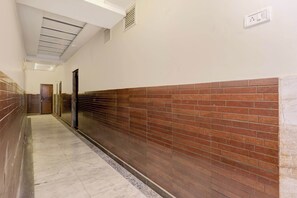 Un pasillo con piso de baldosas, una pared de ladrillo a un lado y una puerta al final.
