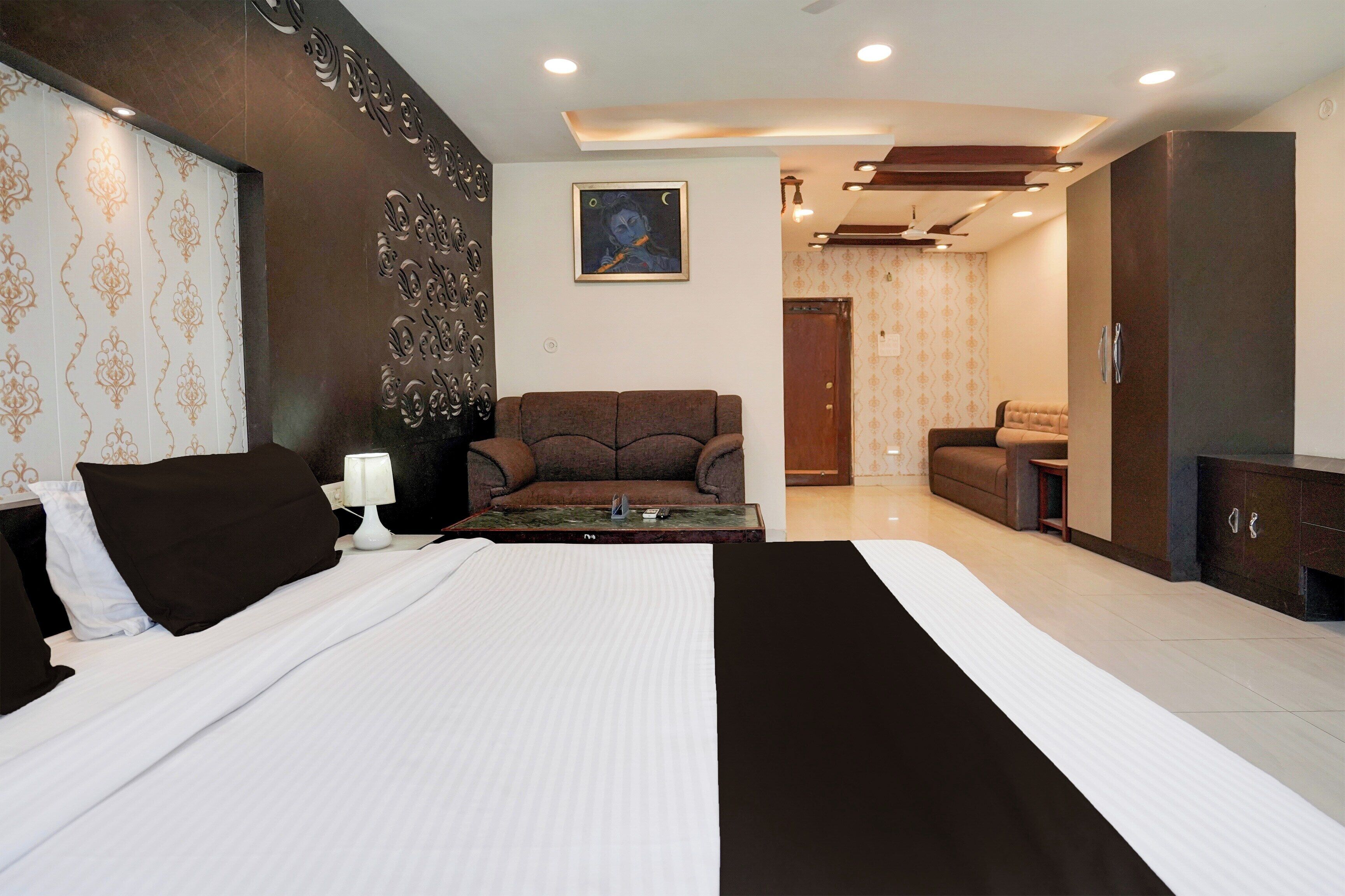 Una habitación de hotel con una cama grande, un sofá, un escritorio y un cuadro en la pared.