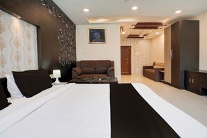 Una habitación de hotel con una cama grande, un sofá, un escritorio y un cuadro en la pared.