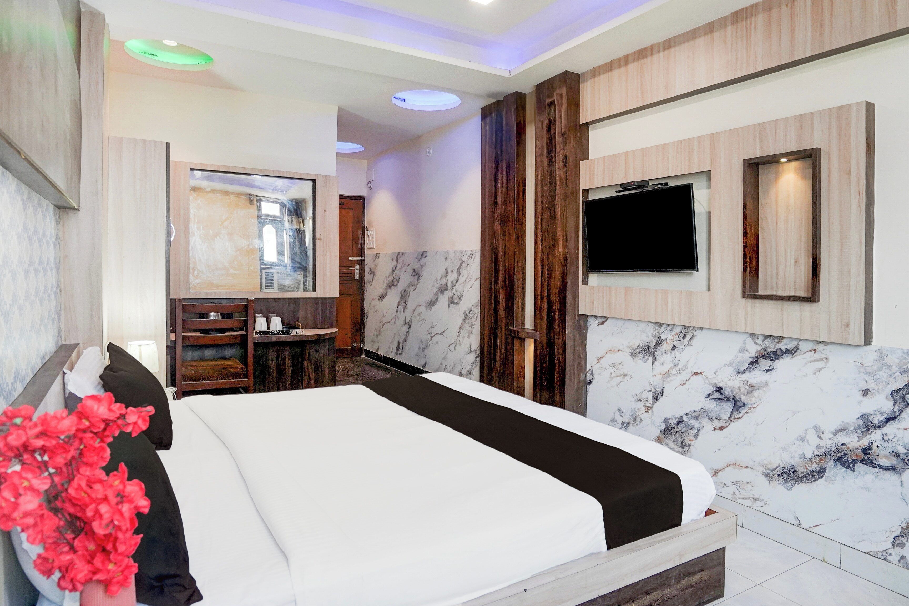 A hotel room with a bed, a television, a mirror, and a bathroom with a shower.