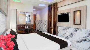 A hotel room with a bed, a television, a mirror, and a bathroom with a shower.