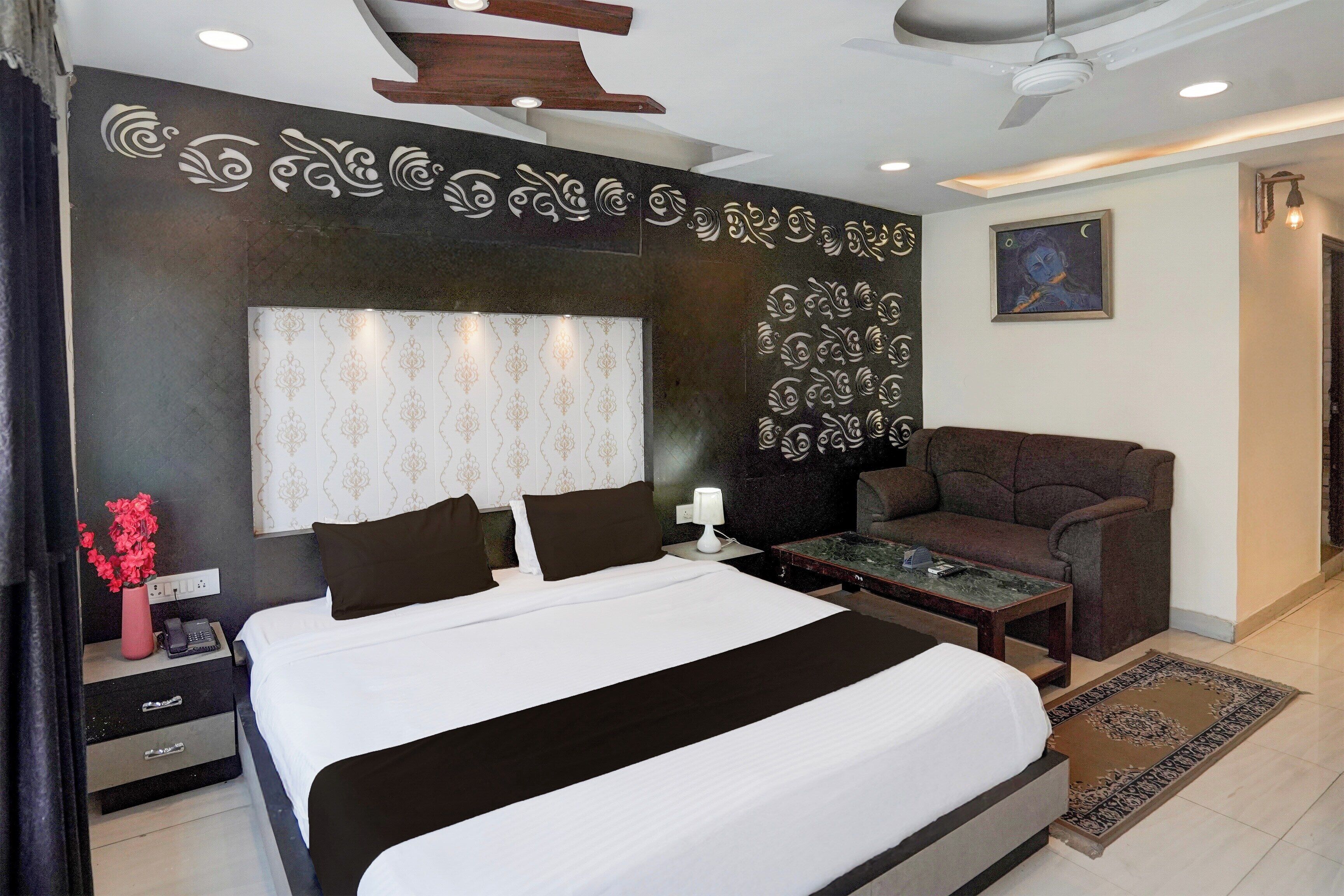 A modern hotel room with a large bed, a sofa, a small table, and a decorative wall.