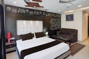 Una habitación de hotel moderna con una cama grande, un sofá, una mesita y un detalle decorativo en la pared.