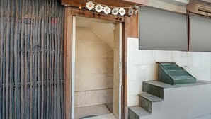 A building entrance with a wooden door, a metal gate, and a staircase leading to a tiled area. - Collection O Kanpur Central Railway (Kanpur)