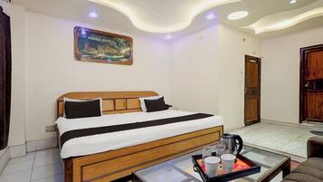A hotel room with a wooden bed, a painting on the wall, a coffee table with a tray, and a door.