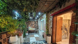Un jardín interior con una estatua, plantas en macetas y un piso a cuadros.
