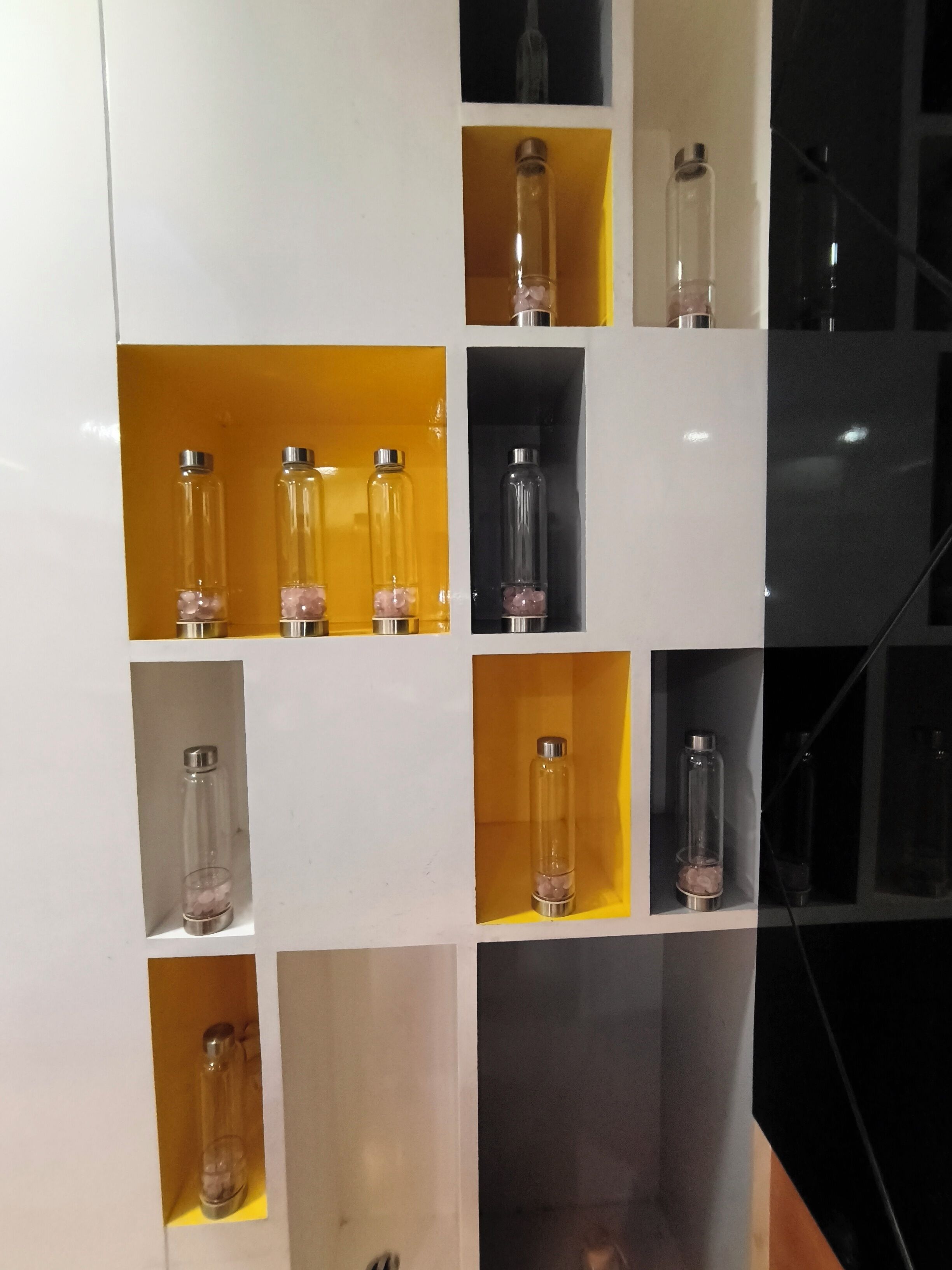A wall with multiple glass-fronted shelves containing various items.