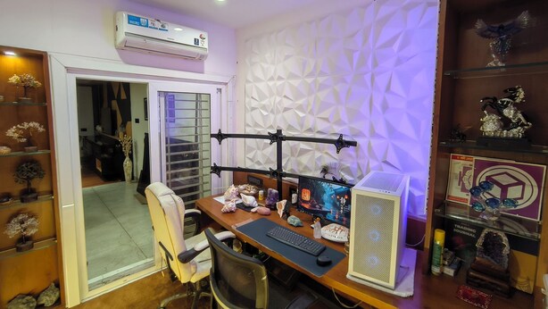 Un despacho en casa con un escritorio, computadora y objetos decorativos.