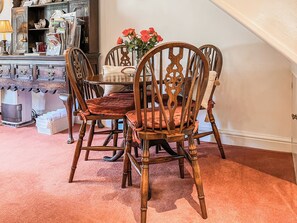 A dining area with a wooden table and chairs, a vase with flowers, and a cabinet with various items. - 1 bedroom accommodation in Clitheroe and the Ribble Valley (Clitheroe and the Ribble Valley)