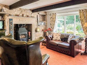 A cozy living room with a stone fireplace, leather furniture, and a view of greenery outside. - 1 bedroom accommodation in Clitheroe and the Ribble Valley (Clitheroe and the Ribble Valley)