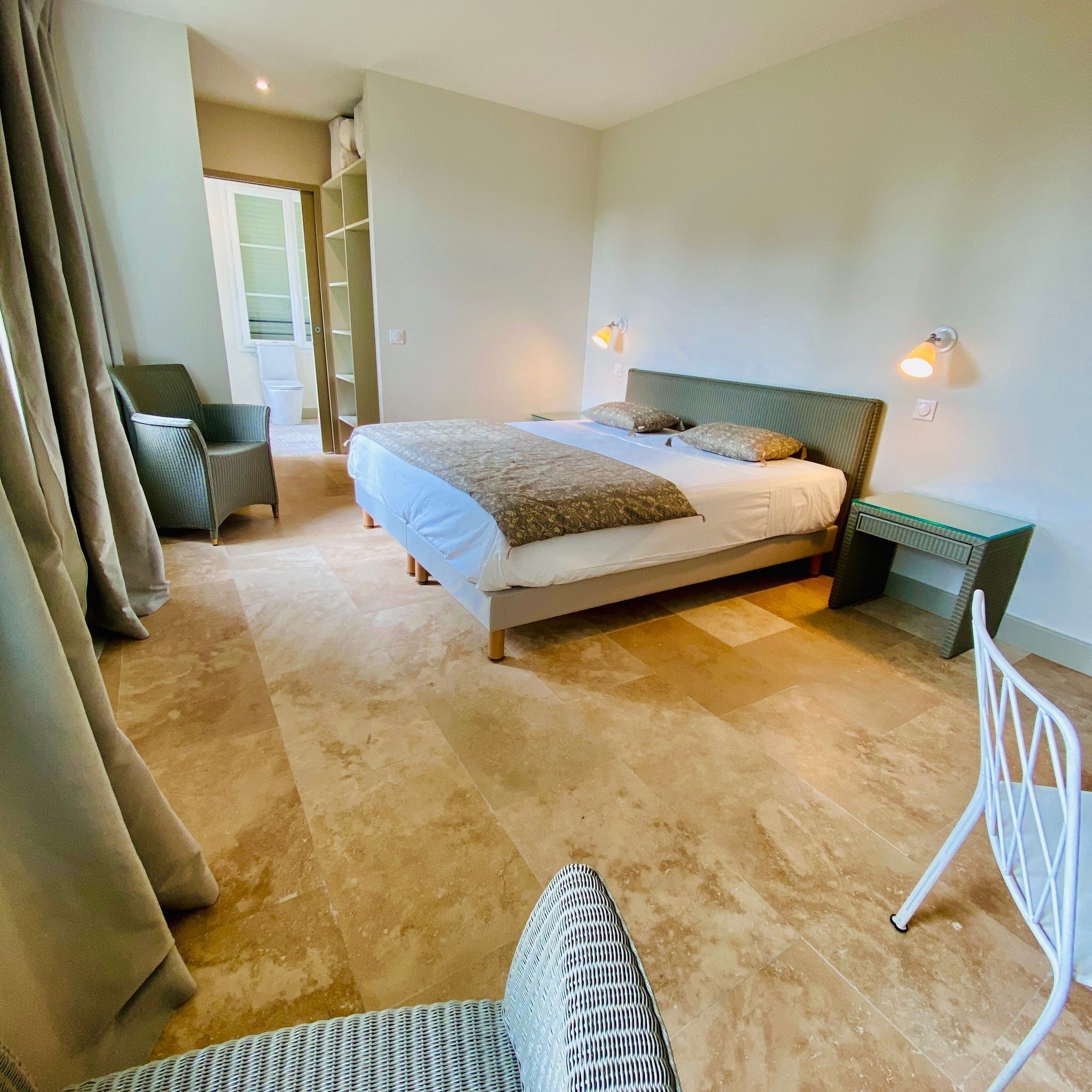 Une chambre à coucher comprenant un lit, deux tables de chevet, une chaise et une armoire.
