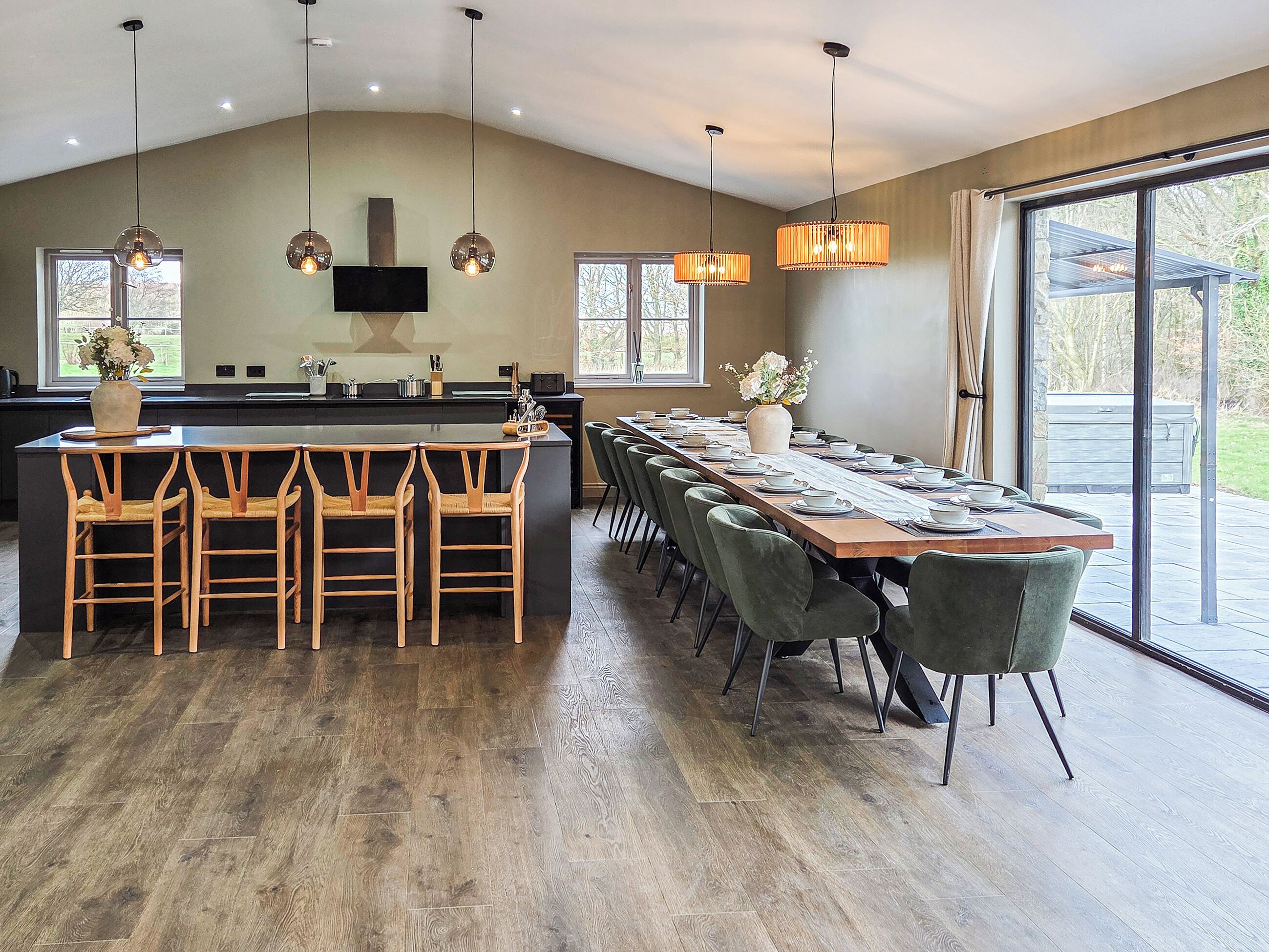 A modern kitchen with a large island, bar stools, and a dining area with a long table set for six.
