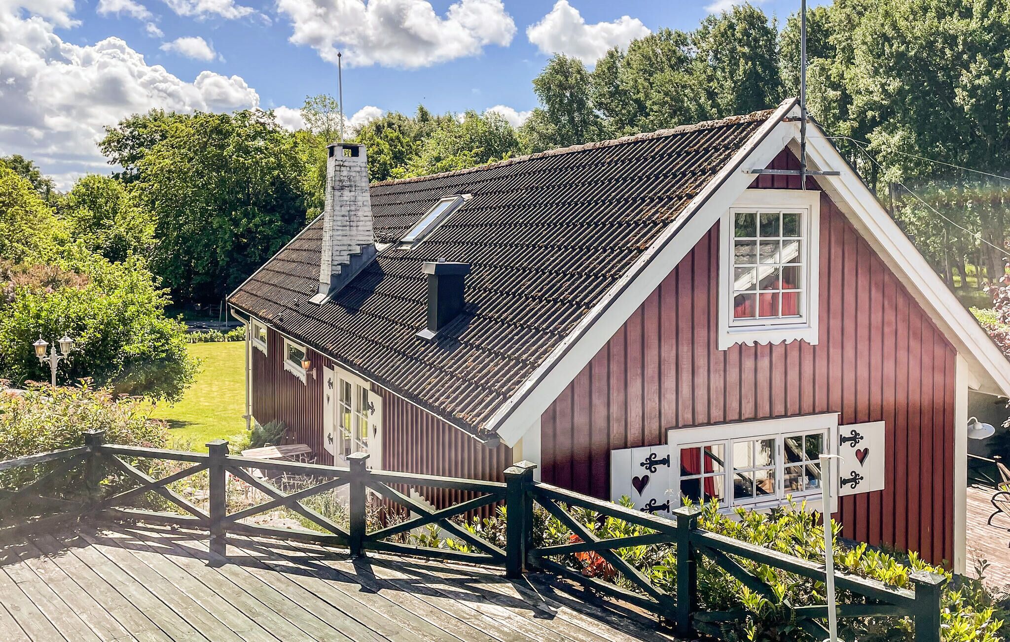 Ett rött trähus med ett sluttande tak, en skorsten och ett fönster med vit ram.