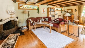 Un salon chaleureux avec une cheminée, un canapé rouge, une table basse en bois et une bibliothèque.