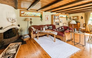 Ein gemütliches Wohnzimmer mit Kamin, einem roten Sofa, einem Holztisch und einem Bücherregal.