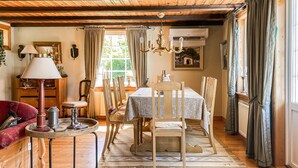 Un coin repas avec une table et des chaises en bois, un lustre et une vue sur l’extérieur par une fenêtre.