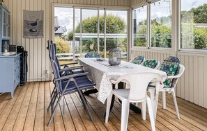 A covered outdoor dining area with a table and chairs, a decorative bird wall hanging, and a view of greenery outside. - 3 bedroom cozy home in Skummeslövstrand (Skummeslövstrand)