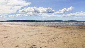 Ein Strand mit blauem Himmel und fernen Hügeln.