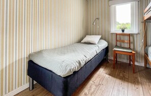 A single bed with a headboard, a bedside table, a chair, and a window with a view of greenery. - 3 bedroom cozy home in Skummeslövstrand (Skummeslövstrand)