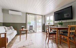 A room with a bed, a table, chairs, a TV, and a sliding glass door leading to an outdoor area. - 3 bedroom cozy home in Skummeslövstrand (Skummeslövstrand)