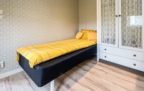 Una habitación con una cama, un armario y una pared con estampado floral.