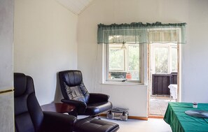 A room with a black leather chair, a small table, a radio, and a window with a curtain. - 1 bedroom beautiful home in Mörrum (Mörrum)
