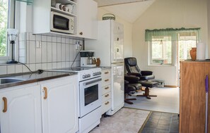 Une cuisine avec des meubles blancs, une cuisinière, un four à micro-ondes et un réfrigérateur.