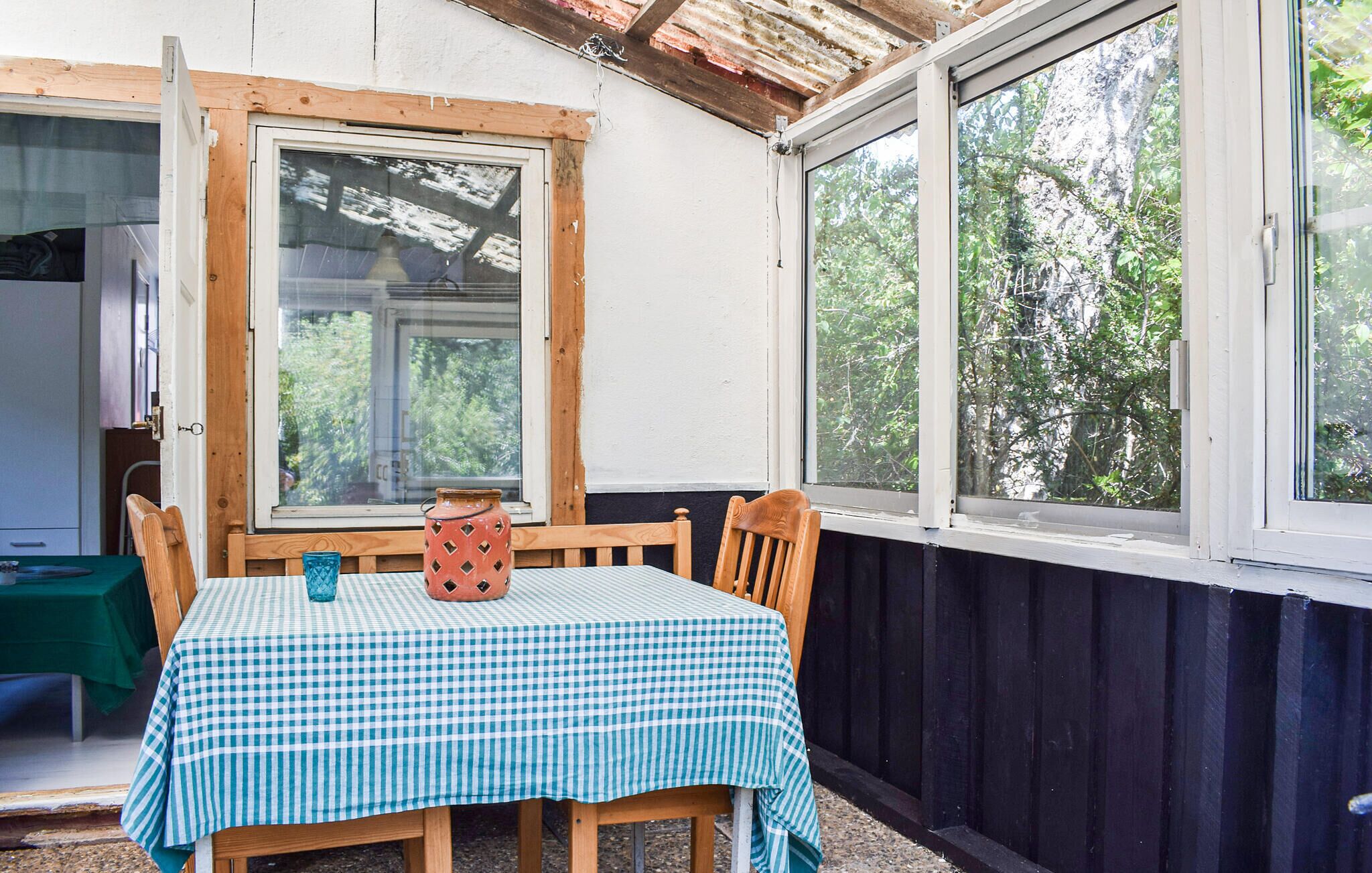 Une table recouverte d’une nappe à carreaux, des chaises en bois et un vase posé sur la table.