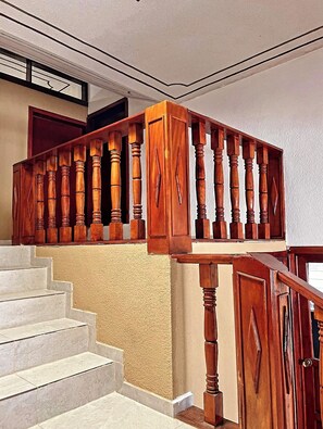 A wooden staircase with a handrail, leading to a landing with a door. - "La Prieta Linda" House (Tamasopo)