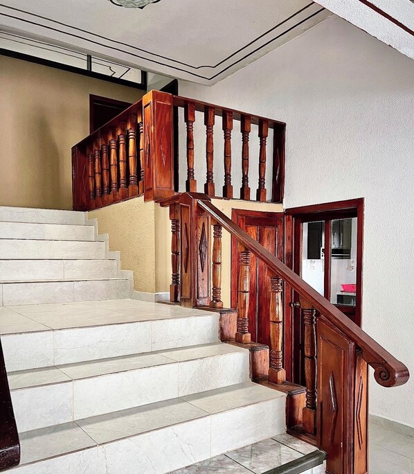 A staircase with wooden balusters and a handrail, leading to an upper floor.