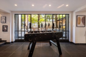 A room with a foosball table, large windows, and artwork on the walls. - Manor in Lille - 600 m² - 16 sleeps - Garden - Terraces - Parking - AC (Lille)