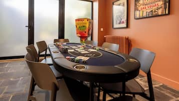 Et casino-bord med spillebrikser og kort, omgivet af stole, i et rum med et 'Welcome to Las Vegas' skilt på væggen.