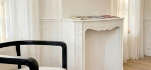 A white console table with books and a red notebook, a black chair in the foreground, and white paneled walls. - Manor in Lille - 600 m² - 49 pers - 15 sleeps - Garden - Terraces - Parking - AC (Lille)