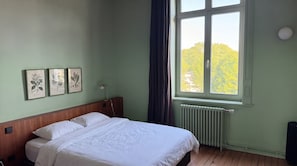 A bedroom with a bed, a window with curtains, a radiator, and framed botanical prints on the wall. - Manor in Lille - 600 m² - 49 pers - 15 sleeps - Garden - Terraces - Parking - AC (Lille)