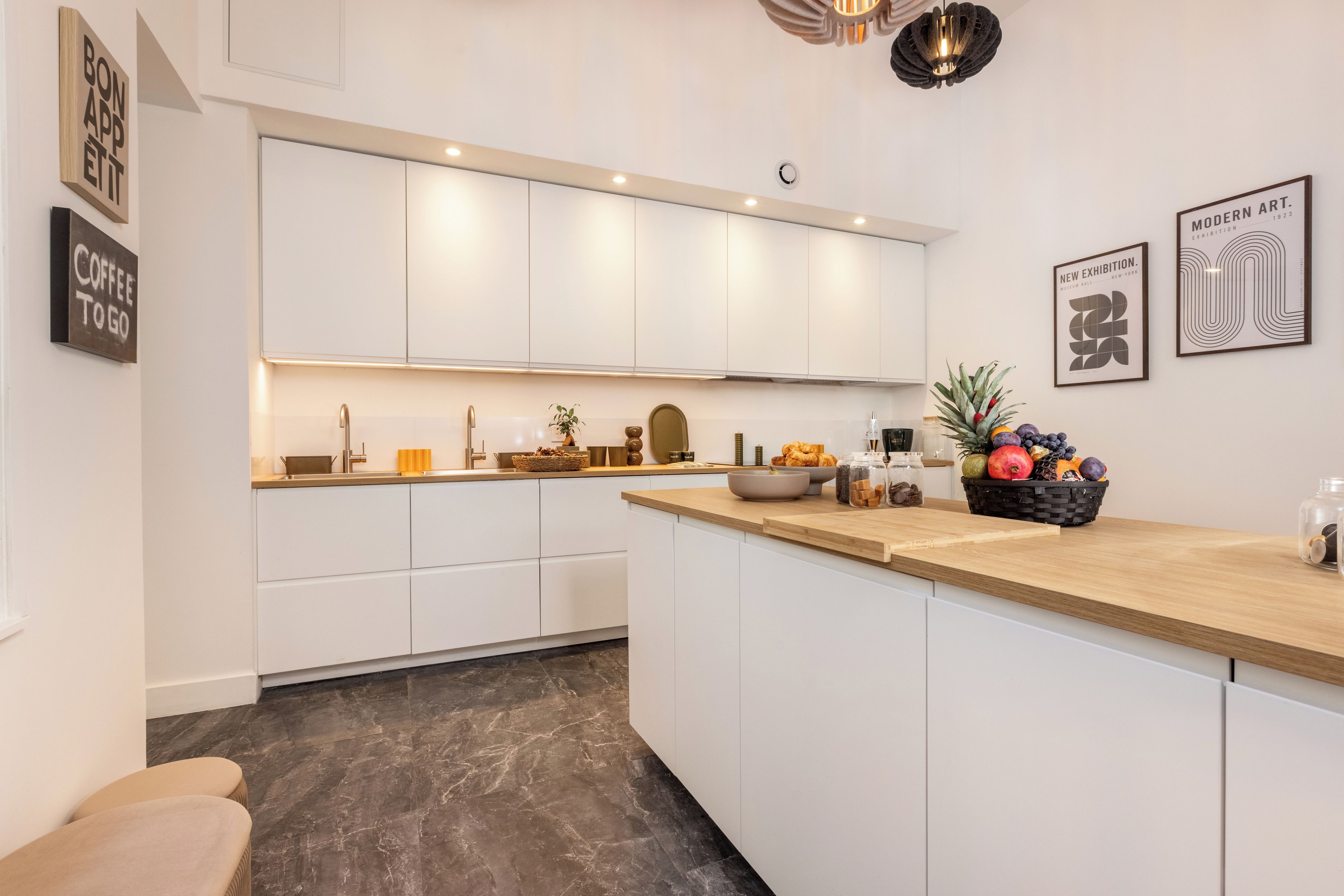 Una cocina moderna con armarios blancos, encimera de madera y un frutero.