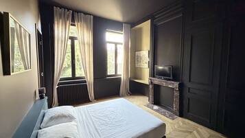 Un dormitorio con cama, chimenea, televisor y ventana con cortinas.