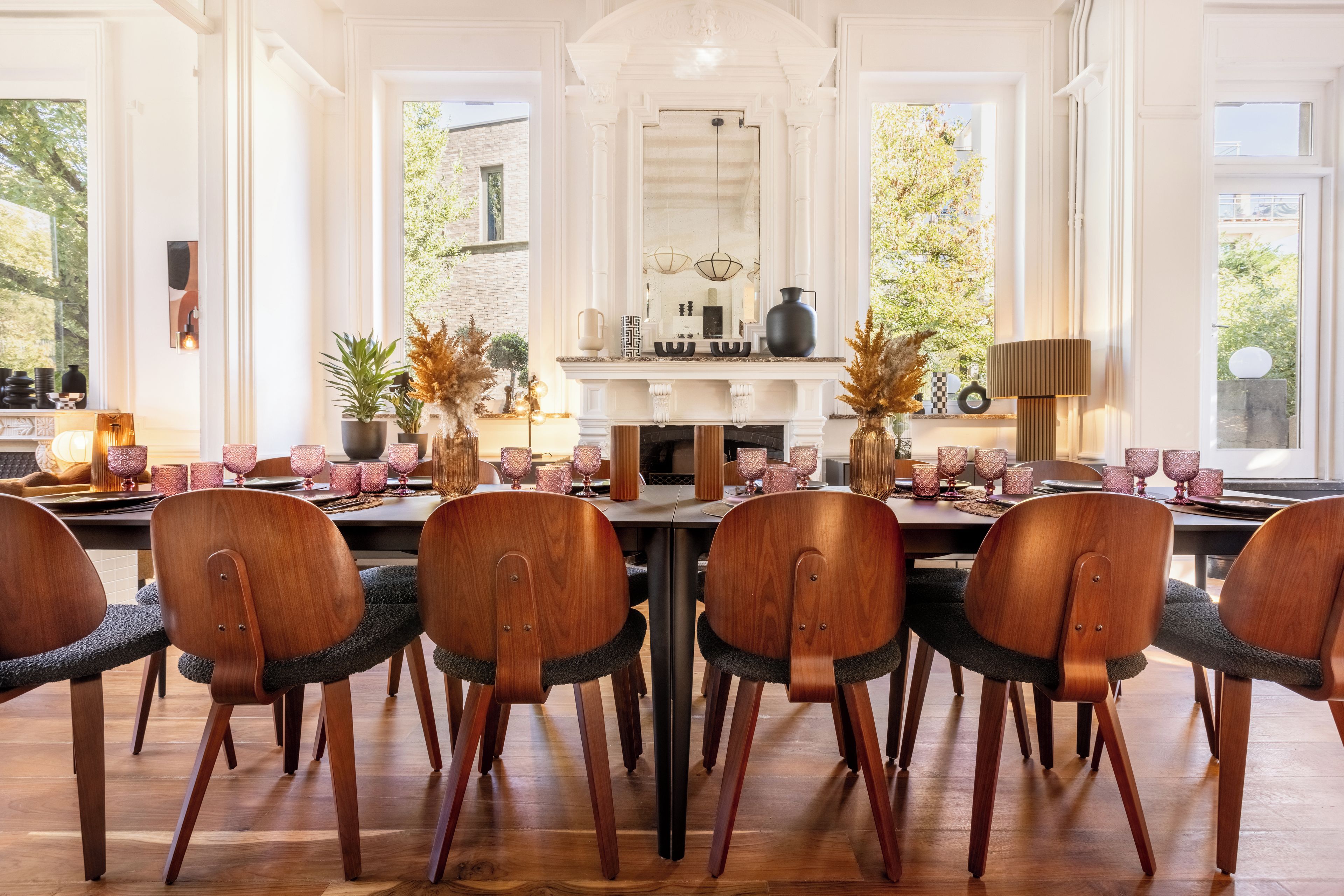 Een eetkamer met een lange tafel, zes houten stoelen en een open haard.
