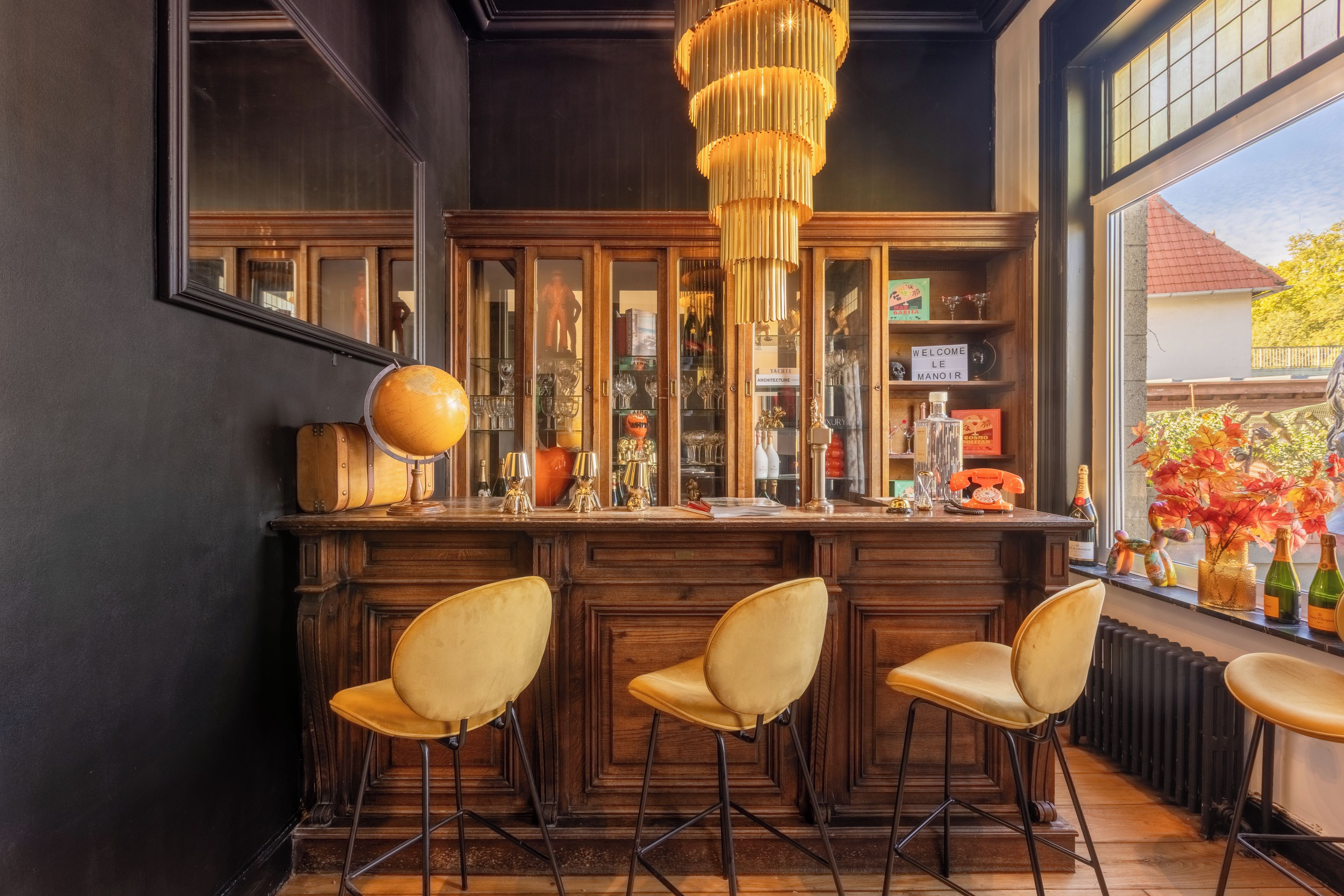 A bar area with wooden bar stools, a globe, and a sign reading 'Welcome'.