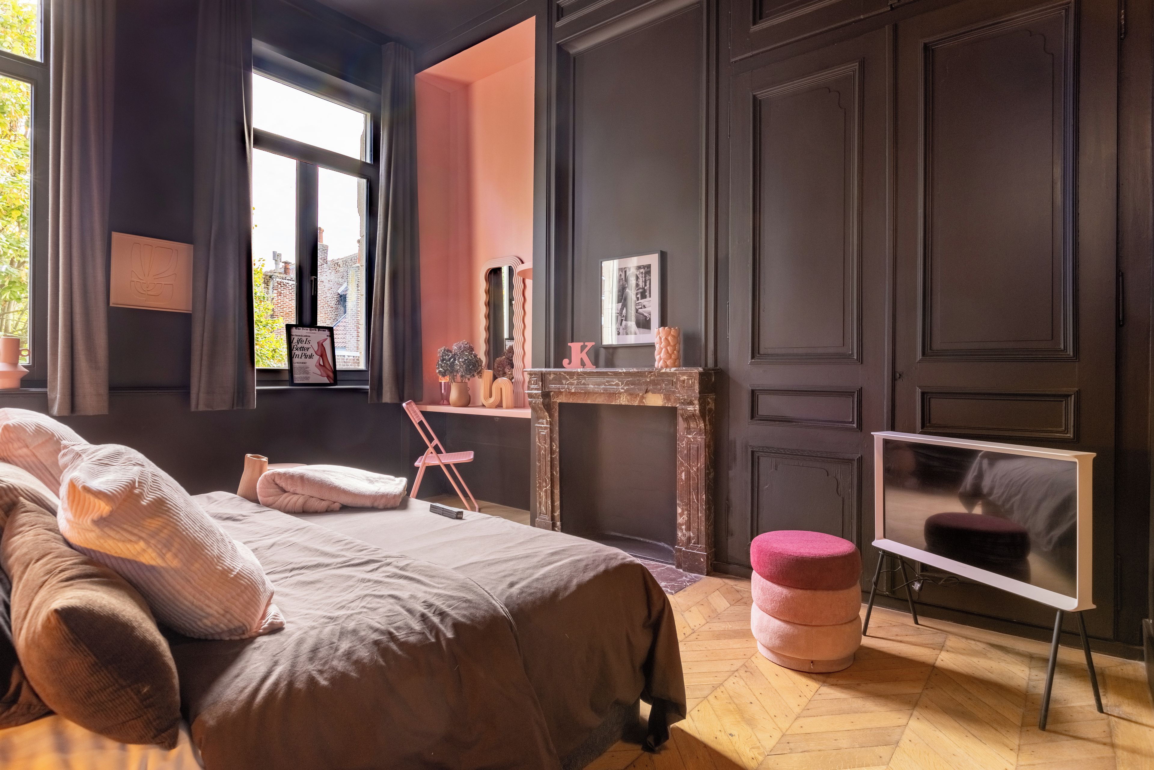 Een slaapkamer met een bed, een stoel, een tafeltje, een spiegel en een televisie.